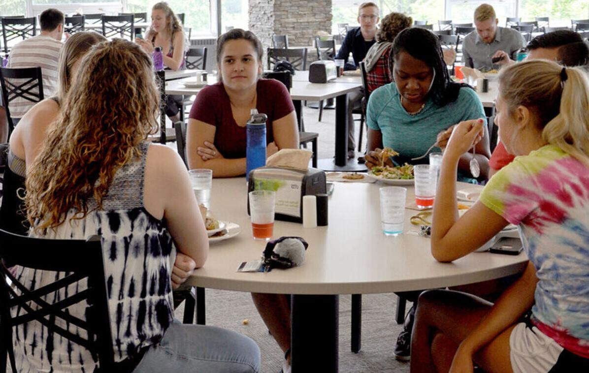 A group of female students talk around a dining hall table